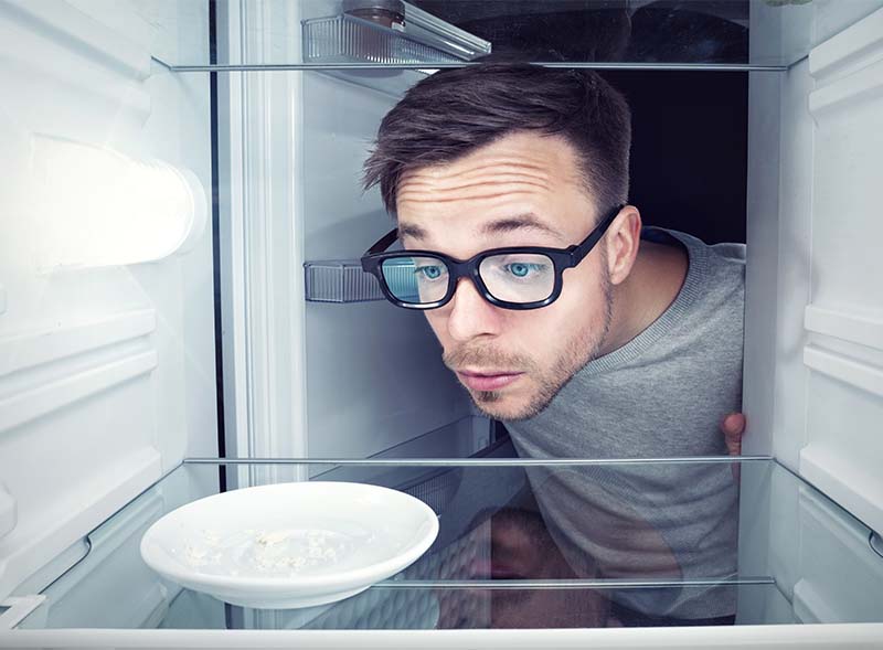 Student schaut in leeren Kühlschrank